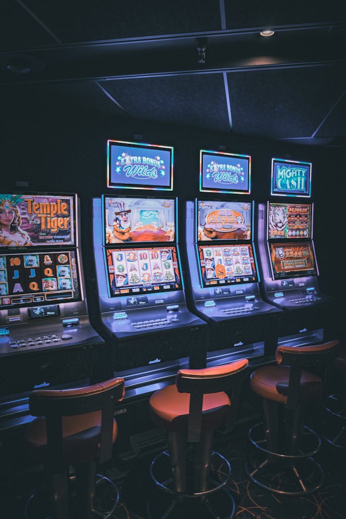 brand-02 Row of illuminated slot machines in a dimly lit, empty casino area.